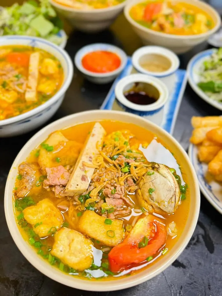 A colorful and appealing bowl of bun rieu, steaming hot, full of rich crab paste